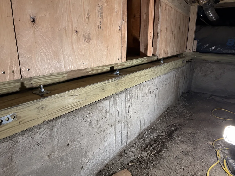 Anchor-bolt retrofit in progress — galvanized anchor bolts with square plate washers fastening a pressure-treated mudsill to the existing concrete stem wall in a California crawl space. PE-stamped per Cal-OES CRMP guidelines.