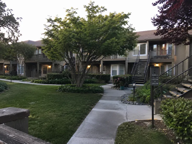 Garden-style two-story apartment building in San Jose, CA, with wood-framed balconies and exterior stair tower — subject to SB-721 inspection.